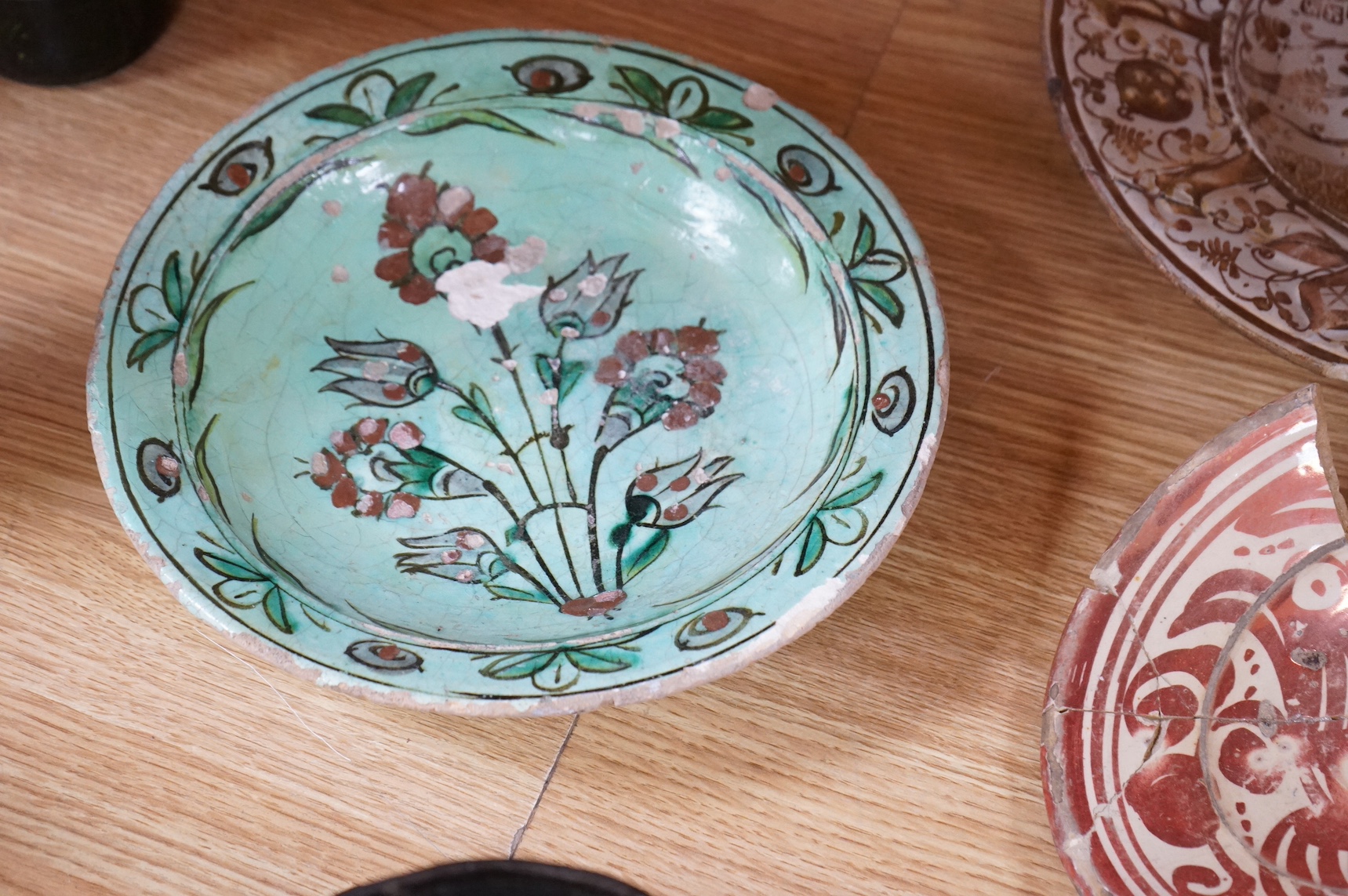 A 16th / 17th century Hispano Moresque copper lustre dish, together with other ceramics, largest 26cm in diameter. Condition - varies
